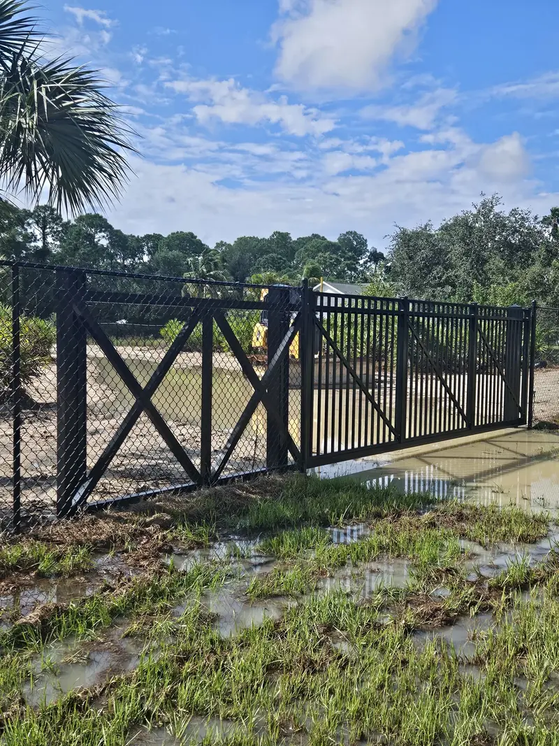 Black chain-link double gate with diagonal braces across a vehicle entrance from Monarca project photos