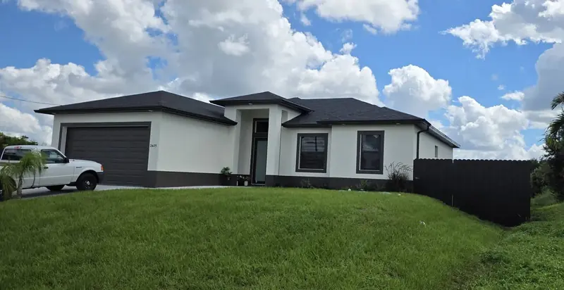 A dark privacy fence ties into the side of a newly built home and encloses the yard behind it.