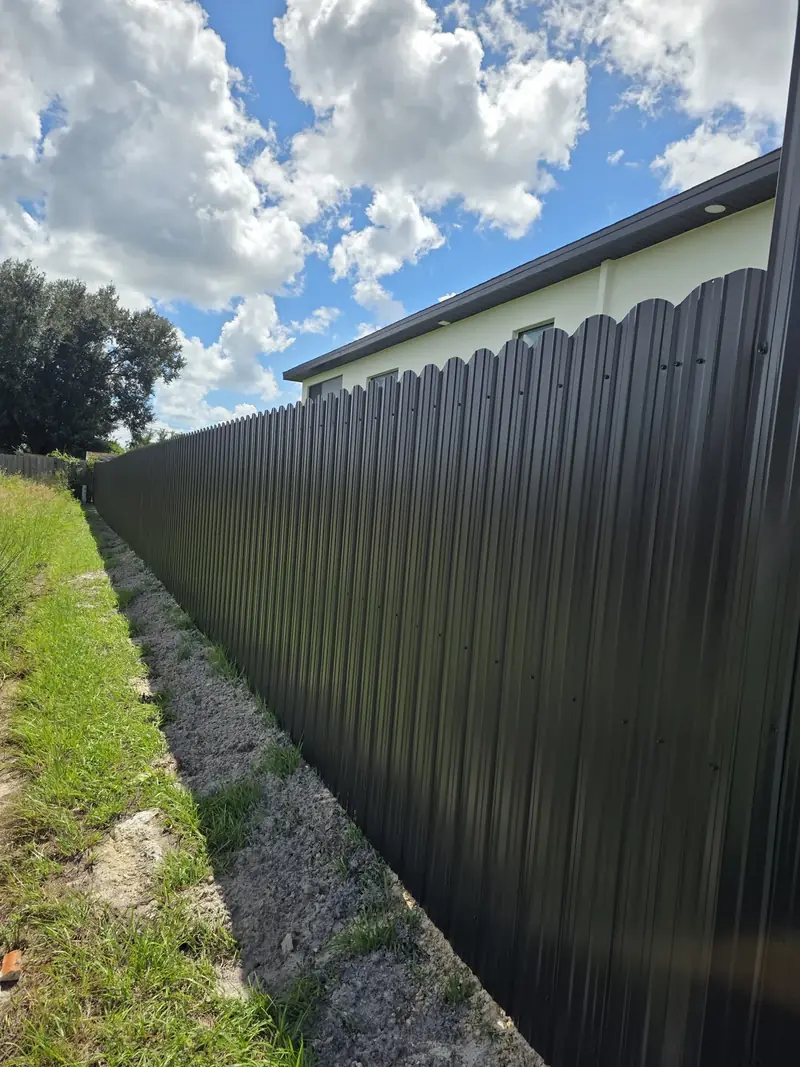 Full-height dark panels run beside the white exterior wall of a home, creating a private boundary along the side yard.