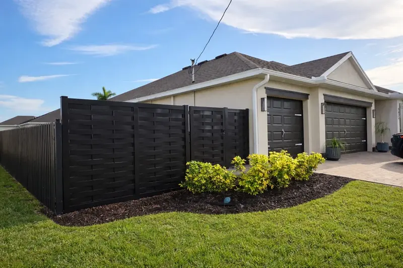 Dark horizontal privacy panels beside a garage and landscaped lawn.