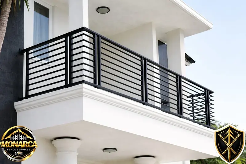 Black horizontal metal railing wrapping the balcony of a white home.