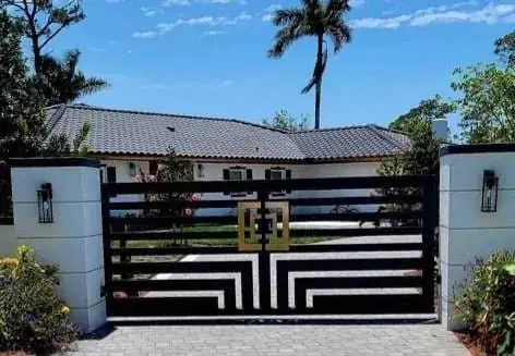 Black horizontal slats and an angular lower pattern frame a gold-toned monogram between white masonry columns.
