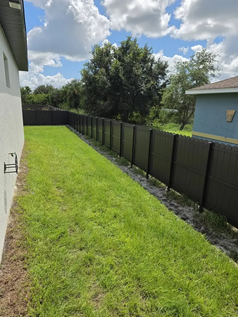 A long, straight run of dark privacy fence follows the side yard from the house to the back of the lot.