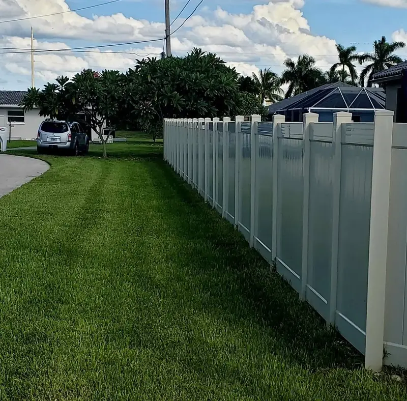 A long vinyl privacy fence beside a lawn and a home.